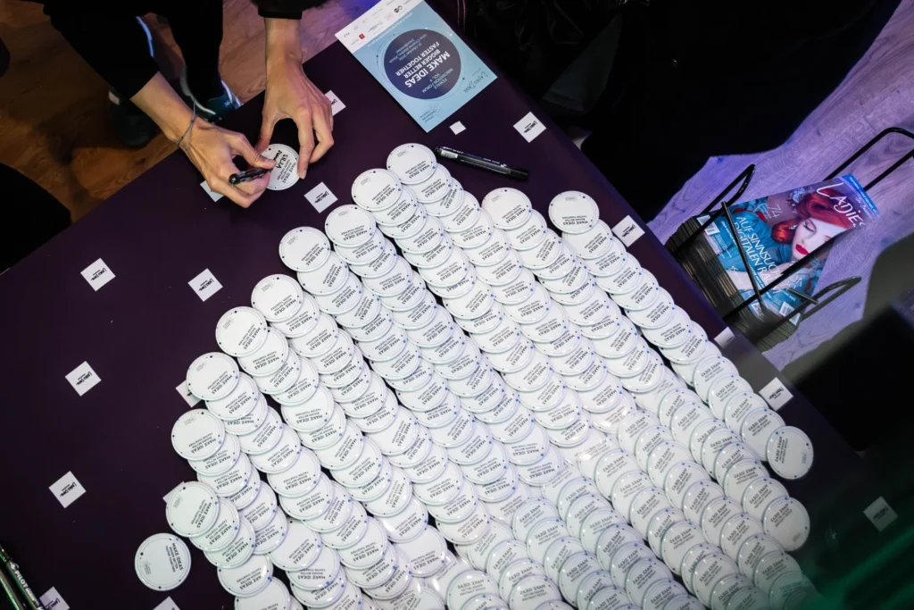 Namensbadges am Eingang des Female Innovation Forum 2026 in Zürich. Eine Teilnehmerin beschriftet ihr Badge für das Networking.