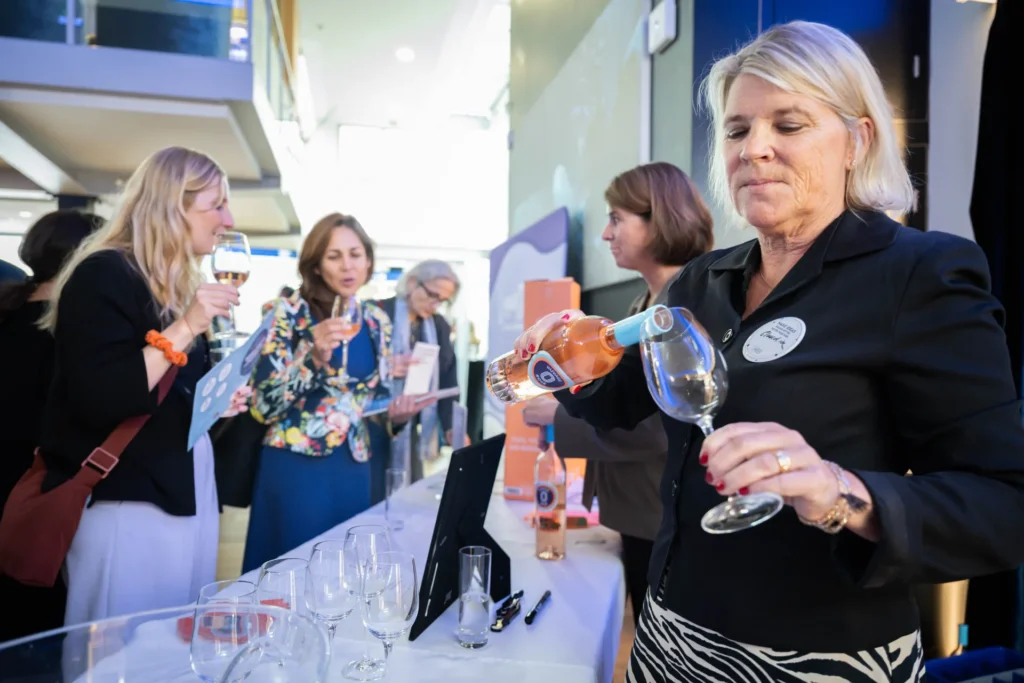 Claudia von Nuvage Wines schenkt alkoholfreien Wein am Female Innovation Forum 2026 aus, während Co-Gründerin Anita Canovas Forjette im Hintergrund mit Gästen spricht.